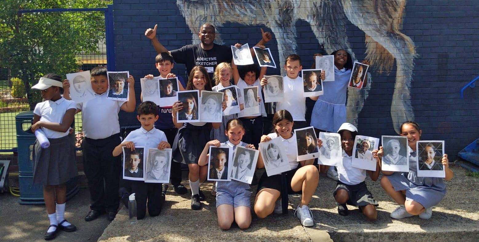 Image of Adebanji Alade outside with pupils and their artwork